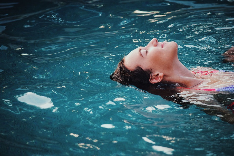 心地よさそうにプールに体を浮かせている女性