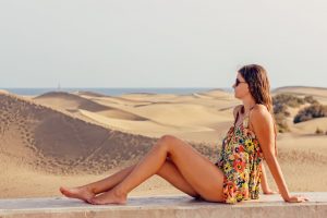 砂漠と海を背景に座っている女性